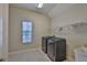 Bright laundry room featuring modern washer and dryer, storage shelf, and window for natural light at 6913 Park Strand Dr, Apollo Beach, FL 33572