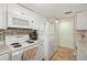 Galley kitchen featuring white appliances, tile backsplash, and updated flooring at 7701 Starkey Rd # 601, Seminole, FL 33777