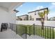 A back patio with a grill overlooks a grassy, fenced yard with a young palm tree, perfect for outdoor relaxation at 7703 S Kissimmee St, Tampa, FL 33616