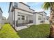 A cozy outdoor patio and green grass area offers a private outdoor living space, enhanced with a young palm tree at 7703 S Kissimmee St, Tampa, FL 33616