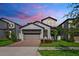Beautiful gray two-story home with a brick driveway and colorful landscaping at 7703 S Kissimmee St, Tampa, FL 33616