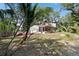 Backyard view of a tan home with brick trim, a screened in porch, two car garage and mature landscaping at 8350 40Th N Ave, St Petersburg, FL 33709