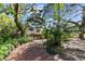 A picturesque view of a brick driveway leading to a tan home surrounded by mature trees and tropical foliage at 8350 40Th N Ave, St Petersburg, FL 33709
