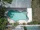 Aerial view of uniquely shaped in-ground swimming pool surrounded by tropical trees at 9802 N Oregon Ave, Tampa, FL 33612