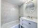 Bright bathroom featuring a tub, tiled walls, and a vanity with a round mirror at 12900 Vonn Rd # D202, Largo, FL 33774