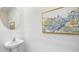 Powder room featuring a round mirror, modern light fixture, pedestal sink and decorative wall art at 17261 Bigleaf Mahogany Ln, Land O Lakes, FL 34638