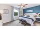 Bright bedroom with a ceiling fan, a window with a view, and a decorative blue accent wall at 17273 Bigleaf Mahogany Ln, Land O Lakes, FL 34638