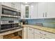 Bright kitchen with stainless steel appliances and white cabinets and modern tile backsplash at 200 1St Ave # 309, St Pete Beach, FL 33706