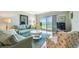 Bright living room with comfortable seating, hardwood floors, and a sliding glass door leading to a balcony at 200 1St Ave # 309, St Pete Beach, FL 33706