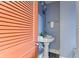 Compact half bath with a pedestal sink, peach colored door, and blue textured walls at 202 39Th S Ave, St Petersburg, FL 33705