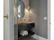 Modern bathroom with sleek black vanity, textured walls, and a stylish oval mirror at 2902 S Beach Dr, Tampa, FL 33629