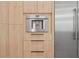 Close up of a modern stainless steel, built-in coffee maker surrounded by light wood cabinetry at 2902 S Beach Dr, Tampa, FL 33629