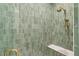Detailed shot of a green-tiled shower with gold showerhead and bench at 2902 S Beach Dr, Tampa, FL 33629