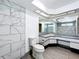 Well-lit bathroom featuring white marble-style tiles, a toilet, and an extra-large mirror at 3900 38Th S St, St Petersburg, FL 33711