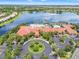 Aerial view of the community center, featuring a large pool, clubhouse, and beautiful landscaping with lake view at 5009 Sandy Brook Cir, Wimauma, FL 33598