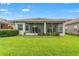 Green lawn is enhanced by screened lanai, plantings, and blue skies at 5009 Sandy Brook Cir, Wimauma, FL 33598