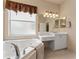 Bright bathroom features a large window, white vanity, and soaking tub at 5009 Sandy Brook Cir, Wimauma, FL 33598