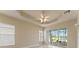 Primary bedroom with tray ceilings, tile floors, and sliding glass doors to screened lanai at 5009 Sandy Brook Cir, Wimauma, FL 33598