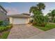 Charming home featuring a paver driveway, lush landscaping, and a two-car garage with beautiful curb appeal at 5009 Sandy Brook Cir, Wimauma, FL 33598