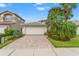 Charming single-story home with a manicured lawn and brick driveway leading to a two-car garage at 5009 Sandy Brook Cir, Wimauma, FL 33598
