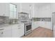 Well-lit kitchen featuring white cabinetry, marble backsplash, countertops and stainless steel range at 5120 3Rd N Ave, St Petersburg, FL 33710