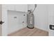 Clean laundry room area with white cabinets, light wood flooring, and a water heater at 5120 3Rd N Ave, St Petersburg, FL 33710
