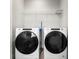 Modern laundry room with front-loading washer and dryer and wire shelving for organized storage at 5270 Neil Dr, St Petersburg, FL 33714
