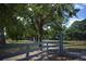 A gated property entrance flanked by mature trees and a gray fence at 6160 Fitzgerald Road, Odessa, FL 33556