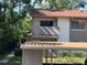 Angle view of a two-story condo featuring a balcony and nearby carport in a sunny, tropical setting at 647 Fairmont Ave # C, Safety Harbor, FL 34695