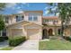 Inviting townhome with a one-car garage and a neatly landscaped yard, under a bright blue sky with scattered clouds at 6954 Hawthorne Trace Ln, Riverview, FL 33578