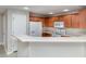 Well-lit kitchen featuring wood cabinets, modern appliances, a breakfast bar, and a view into the adjacent living area at 6954 Hawthorne Trace Ln, Riverview, FL 33578