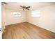 A spacious bedroom featuring two windows, a ceiling fan, and modern wood-look laminate flooring at 7904 Judith Cres, Port Richey, FL 34668