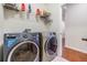 Modern laundry room with front-loading washer and dryer, storage shelves and door to hallway at 8296 Olive Brook Dr, Wesley Chapel, FL 33545