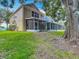 View of the back of the property featuring green grass, mature trees, and multiple enclosed patios at 8576 Sandy Beach St, Tampa, FL 33634