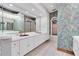 Elegant bathroom featuring a double vanity with white cabinets, ornate wallpaper and a large mirror at 8827 Scout Lake Ct, New Port Richey, FL 34654