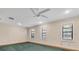 Spacious bedroom with green carpet, ceiling fan, and three large windows for ample natural light at 8827 Scout Lake Ct, New Port Richey, FL 34654