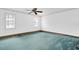 A large, carpeted bedroom with a ceiling fan and two windows at 8827 Scout Lake Ct, New Port Richey, FL 34654