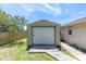 Exterior shot of detached, one-car garage with roll-up door, wood ramp, and partial view of fenced backyard at 8827 Scout Lake Ct, New Port Richey, FL 34654