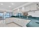 A bright kitchen with white cabinets and teal countertops overlooks the pool area and backyard at 8827 Scout Lake Ct, New Port Richey, FL 34654