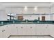 White kitchen cabinets with teal countertops offer ample storage and a view of the living space at 8827 Scout Lake Ct, New Port Richey, FL 34654
