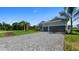 A beautiful single-story home with a large paver driveway, grey stucco, a 2-car garage, and tropical landscaping at 9295 Rosebud Cir, Port Charlotte, FL 33981