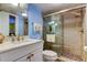 Well-lit blue bathroom with white vanity and step-in shower featuring decorative tile at 9484 Tara Cay Ct # 8, Seminole, FL 33776