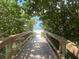 Wooden boardwalk framed by trees leads to a sunny white sand beach at 9484 Tara Cay Ct # 8, Seminole, FL 33776