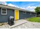 Home exterior with a bright yellow door, gravel landscaping, and a barbecue grill for outdoor enjoyment at 1005 Monroe St, Plant City, FL 33565