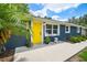 Inviting front porch featuring a bright yellow door, seating, and manicured landscaping at 1005 Monroe St, Plant City, FL 33565