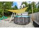 Backyard with an above-ground pool and a tanning overhang with blue lounge chairs surrounded by lush greenery at 1005 Monroe St, Plant City, FL 33565