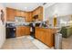 Functional kitchen with oak cabinetry, tile floors, and an open layout flowing to the living room at 1013 N Bask Dr, Tampa, FL 33603