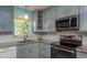Well-equipped kitchen with gray cabinets, granite countertops, and stainless steel appliances at 1065 Tartan Dr # C, Palm Harbor, FL 34684