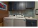 Laundry room with blue cabinets, brick backsplash, washer, dryer, and sink at 1065 Tartan Dr # C, Palm Harbor, FL 34684