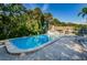 A clear blue swimming pool surrounded by a brick patio and lush greenery, offering a refreshing outdoor space at 1065 Tartan Dr # C, Palm Harbor, FL 34684